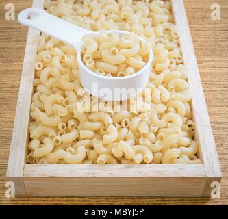 Food and Cuisine, Uncooked and Dried Elbow Macaroni or Gomiti Pasta in Plastic Measuring Cup. Stock Photo