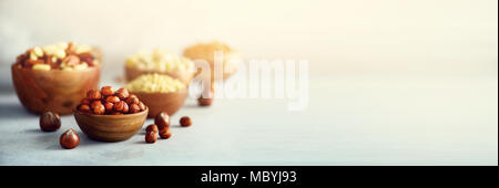 Hazelnuts in wooden bowl. Food mix background, top view, copy space, banner. Assortment of nuts - cashew, hazelnuts, walnuts, pistachio, pecans, pine nuts, peanut, raisins. Stock Photo