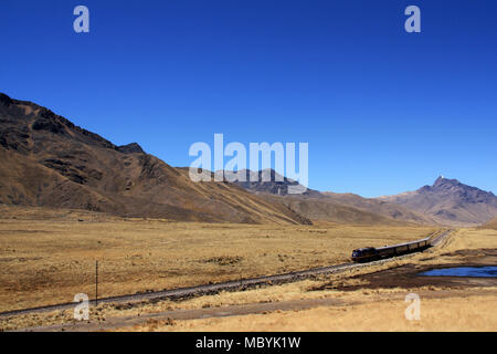 A Train making it's Way through a wide Valley within the Andes Mountain Range in Peru Stock Photo