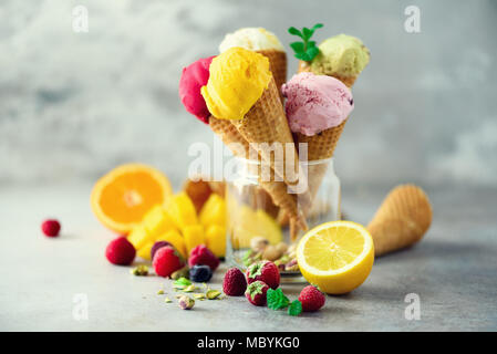 Colorful ice cream balls in waffle cones with different flavors - mango, lime, mint, pistachio, orange, strawberries, raspberries, blueberries. Summer concept Stock Photo