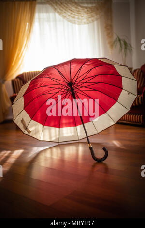 Two-tone burgundy with beige open umbrella standing on the floor Stock Photo