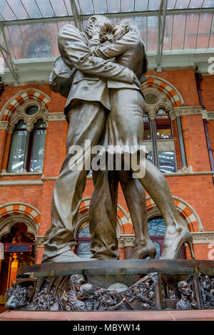 The artwork entitled The Meeting Place by British artist Paul Day stands in the main concourse at St. Pancras Station, on 10th April 2018, in London, England. The Meeting Place is a 9-metre high, 20-tonne bronze statue that stands at the south end of the upper level of St Pancras evoking the romance of travel through the depiction of a couple locked in an amorous embrace. The statue, is reported to have cost £1 million and was installed as the centrepiece of the refurbished station. The work, commissioned by London and Continental Railways, is modelled on the sculptor and his wife. Stock Photo