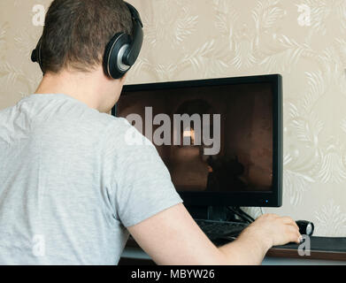 Man in headphones playing computer shooter game. Stock Photo