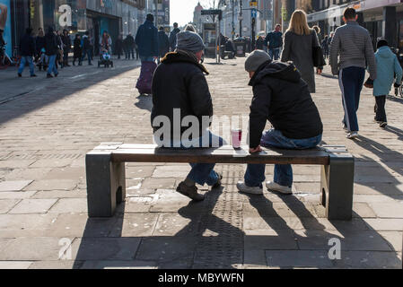 Two men sitting on a bench at the top of Northumberland Street,Newcastle upon Tyne, north east England, UK. Stock Photo