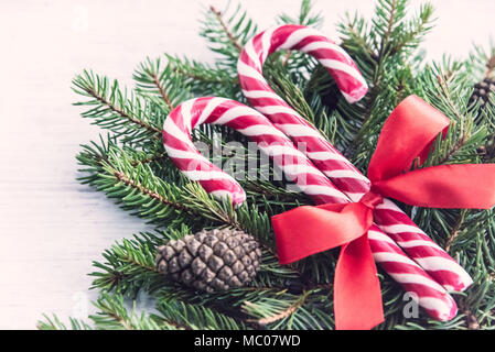 Close up of a fir tree and candy cones tied with a red bow over an old white wood background. Christmas decoration background. Stock Photo