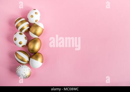 Top view of easter eggs colored with golden paint. Various striped and dotted designs. Pink background. Stock Photo