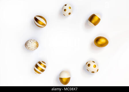 Top view of easter eggs colored with golden paint in differen patterns arranged in circle. Various striped and dotted designs. White background. Copy  Stock Photo
