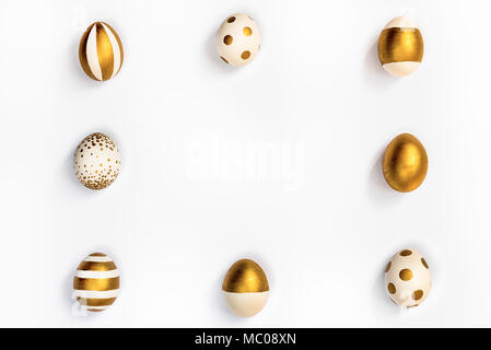 Top view of easter eggs colored with golden paint in differen patterns arranged in square. Various striped and dotted designs. White background. Copy  Stock Photo