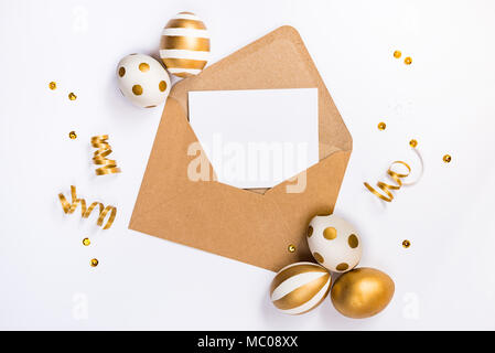 Easter festive decoration. Top view of easter eggs colored with golden paint in differen patterns and empty mock-up card in a kraft envelope. Various  Stock Photo
