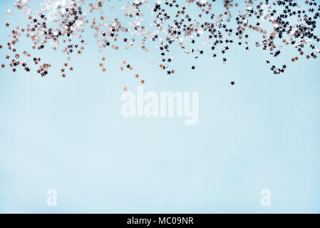 Star shaped silver sequins over blue background. Copy space. Stock Photo