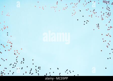 Star shaped silver sequins over blue background. Copy space. Stock Photo