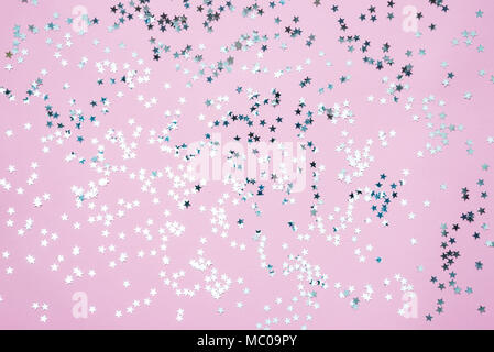 Star shaped silver sequins over pink background. Stock Photo