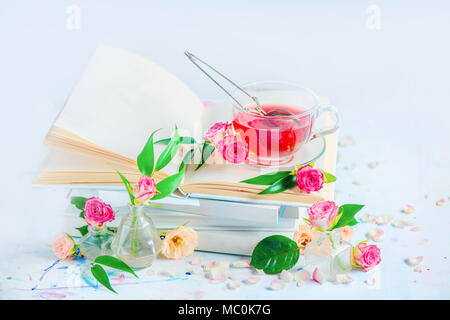 Stack of white books with a cup of herbal tea. High key still life with copy space. Spring leisure and reading concept. White on white. Stock Photo