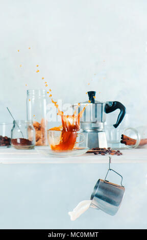 Kitchen shelf with Moke pot, a cup of espresso with a dynamic splash, milk pitcher and a jar of coffee beans. Brewing coffee high key concept with cop Stock Photo