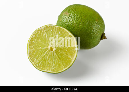 Whole lime and other one cut in half, isolated on white background. Stock Photo