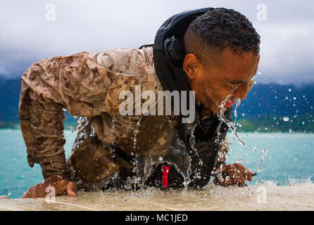 Pfc. Michael Prince, an infantryman with Detachment 4th Force Reconnaissance Company, pulls himself from the water during a run, fin, run training event at Davie Point, Marine Corps Base Hawaii, Jan. 22, 2018. The event consisted of a two km fin and a 2.5 mile run, which had to be completed in less than 90 minutes. The unit’s training program aims to prepare students for the stresses of the Basic Reconnaissance Course by offering a broad, realistic curriculum, challenging them both mentally and physically. (U.S. Marine Corps photo by Lance Cpl. Luke Kuennen) Stock Photo