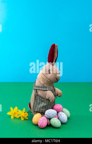 Vintage toy rabbit, bunny, with a pile of chocolate easter eggs. Stock Photo