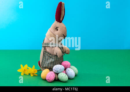 Vintage toy rabbit, bunny, with a pile of chocolate easter eggs. Stock Photo