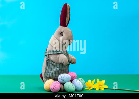 Vintage toy rabbit, bunny, with a pile of chocolate easter eggs. Stock Photo