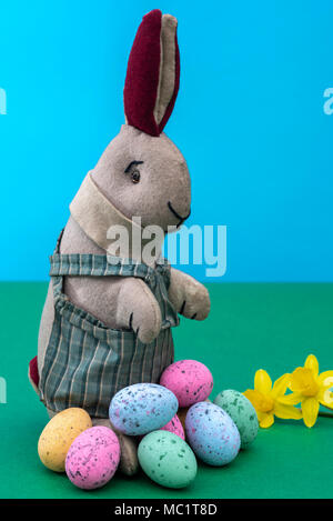 Vintage toy rabbit, bunny, with a pile of chocolate easter eggs. Stock Photo
