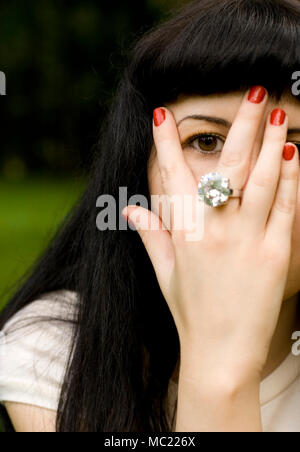pretty brunet girl covering her face, looking through fingers Stock Photo