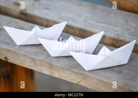 Three white paper boats on wooden bench, closeup Stock Photo