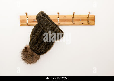 Winter wool cap with a furry ball hanging on a hat stand on white background Stock Photo