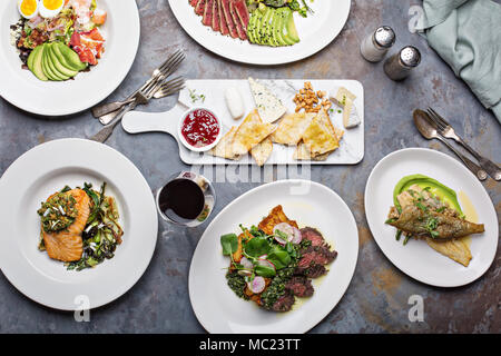Big dinner table overhead view with steak and fish Stock Photo