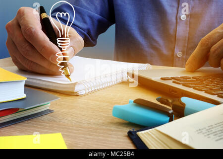 Ideas concept. Businessman writing in the note and light bulb. Creative process. Stock Photo