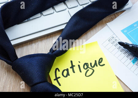 Tie and memo stick with word fatigue on an office desk. Stock Photo