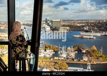 Unrecognizable girl in hijab looking on Amsterdam from aerial view, Holland Stock Photo