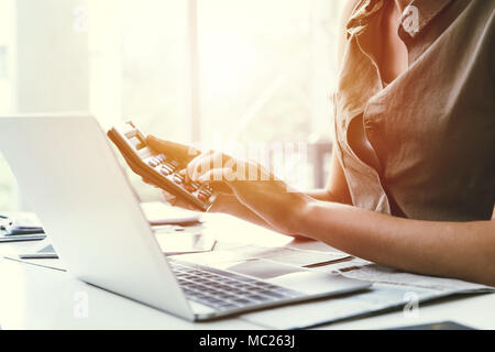 Business office worker using calculator to calculate cost financial while working with laptop computer Stock Photo