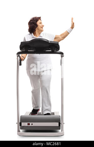Full length profile shot of a mature woman walking on a treadmill and making high-five gesture isolated on white background Stock Photo