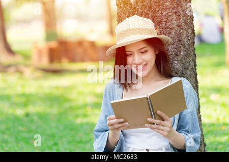 Beautiful Asian woman reading book in the park on holiday self-learning Stock Photo