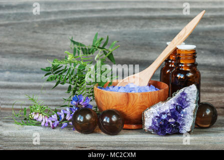 Spa concept. Salt for baths, bottles with essential oils, stone amesist and blue flowers on an old wooden background Stock Photo