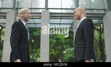 two corporate business people standing and talking in lobby of modern office building. Stock Photo