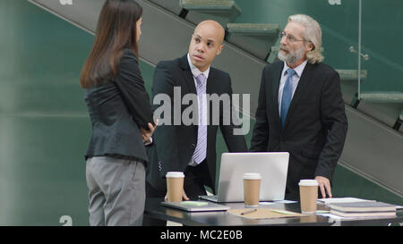 multiethnic corporate people meeting in office discussing business using laptop computer in modern office. Stock Photo