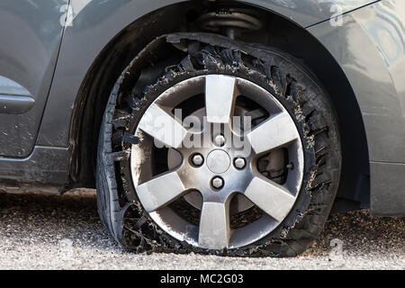 Destroyed blown out tire with exploded, shredded and damaged rubber on a modern suv automobile. Flat low profile tyre on an alloy rim, ripped open Stock Photo