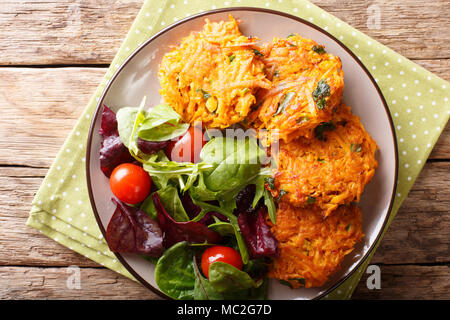 Fritters of sweet potatoes with greens and fresh salad on a plate close-up. horizontal top view from above Stock Photo