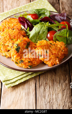 Fritters of sweet potatoes with greens and fresh salad on a plate close-up. vertical Stock Photo