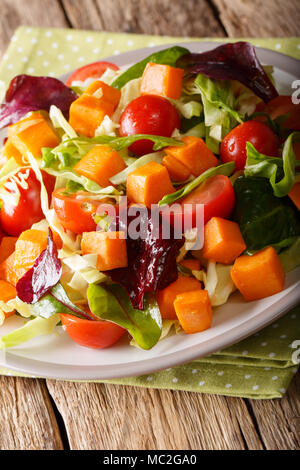 Delicious organic salad of sweet potato with fresh vegetables close-up on a plate on a table. vertical