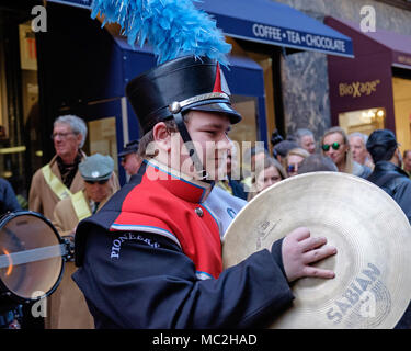 High school boy with cymbals in marching band, St. Patrick's Day Parade, New York, 2018. Red, white & black band uniform, black hat, blue feathers. Stock Photo