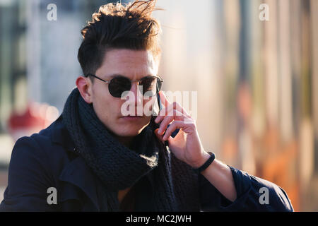 young man with sunglasses takes a phone call Stock Photo