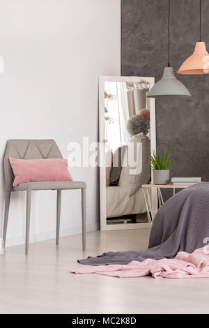 Mirror standing in the corner of a bright bedroom interior with textured wall and pastel lamps Stock Photo