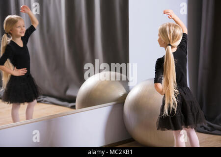Blonde girl dancing in front of the mirror during a ballet lesson for youth Stock Photo