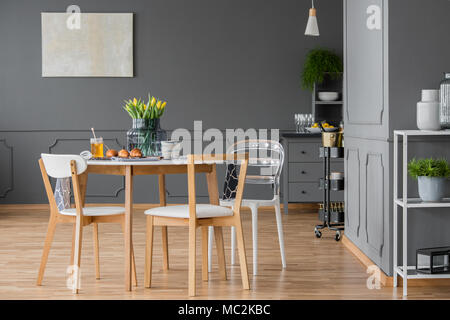 Minimalist, wooden set of dining furniture in the middle of a designer open space loft interior with simple decor and elegant, dark gray walls Stock Photo