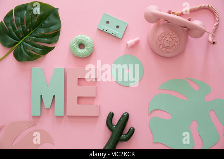 Pink phone, cactus and yellow leaf on pink background with letters M and E Stock Photo