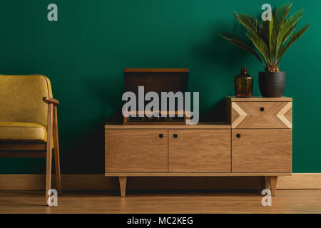 Close-up of a retro wooden dresser with a hipster record player in a minimalist dark green living room interior Stock Photo