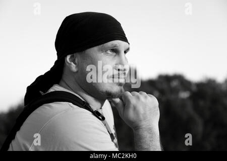 Black and white photo. Smiling young man in bandana dreams of something. Stock Photo
