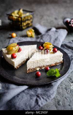 No bake yoghurt and coconut cake with almond, dried plums, chia seeds crust and topped with fresh cranberries and Physalis Stock Photo